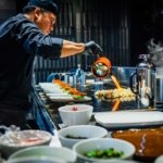 man in blue jacket pouring water on white ceramic bowl