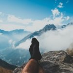 person in black sock sitting on rock formation during daytime