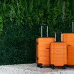 three orange suitcases sitting on a pedestal in front of a green wall