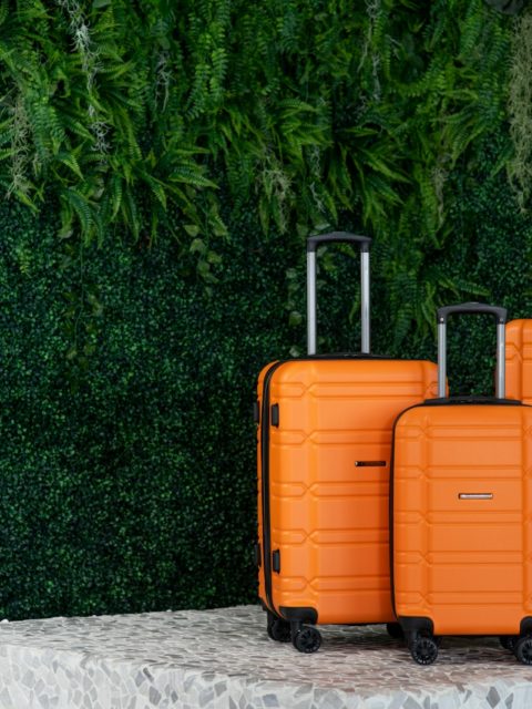 three orange suitcases sitting on a pedestal in front of a green wall