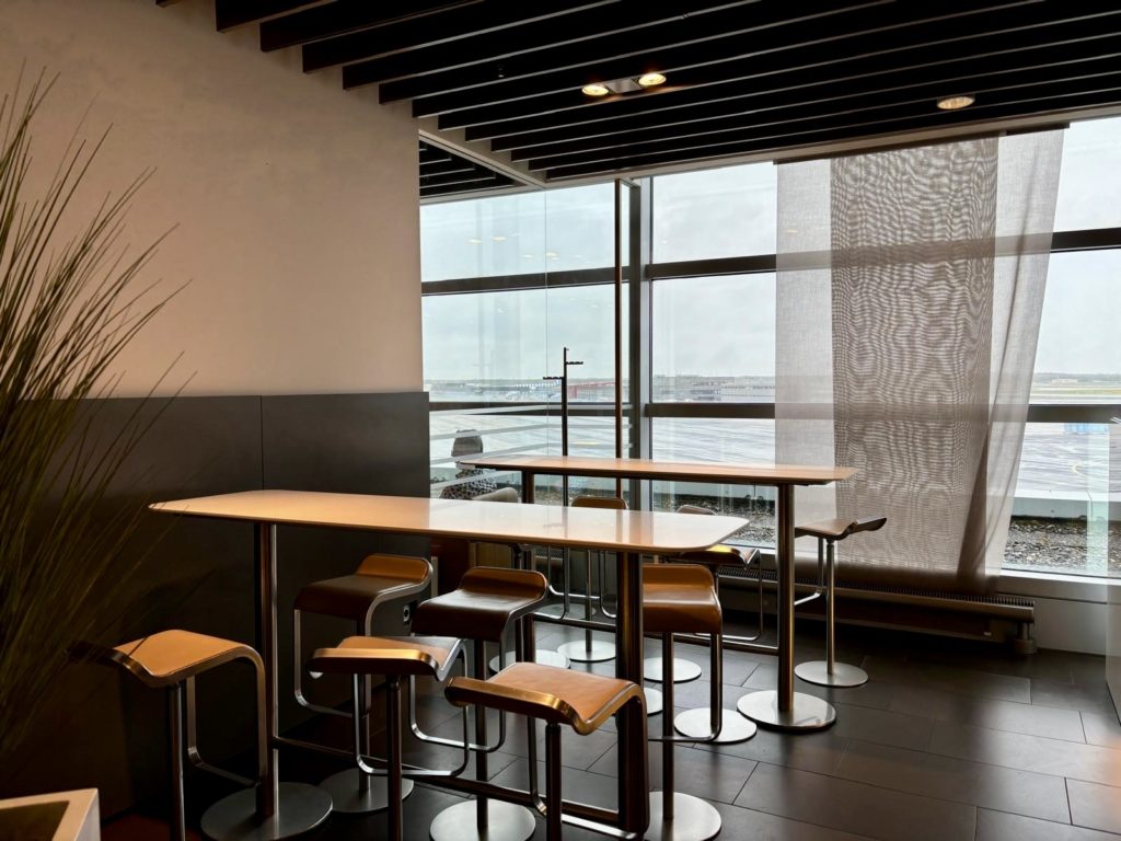 Un espace avec des tables hautes et vue sur le tarmac du Lufthansa Business Lounge A26 (Schengen) à Frankfurt