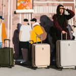a woman standing next to two suitcases in front of a mural
