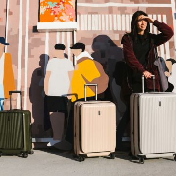 a woman standing next to two suitcases in front of a mural