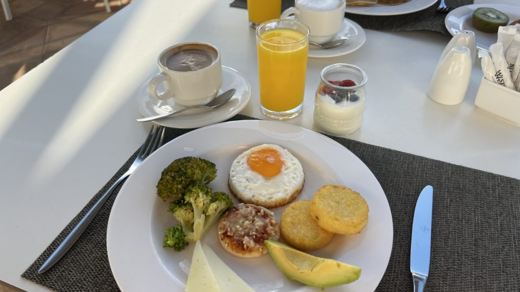 Une assiette de petit-déjeuner composée d'un jus de fruit, d'un café et de légumes et pommes de terres