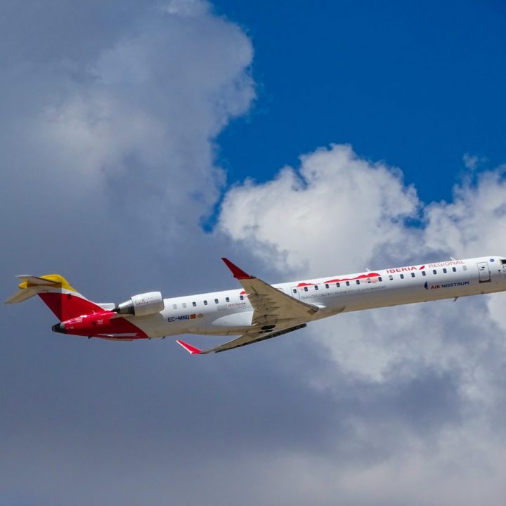 white and red airplane across white clouds