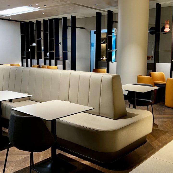 Un espace avec des sièges et des tables au salon Star Alliance Lounge à l'aéroport d'Amsterdam Schiphol