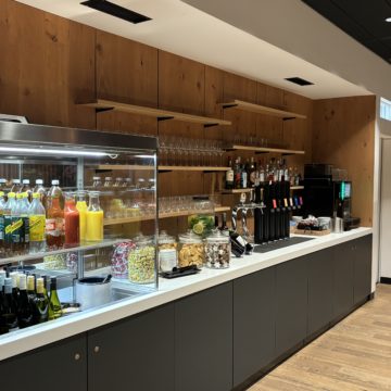 Un buffet avec des boissons froides, des fontaines à sodas et une machine à café au salon Business de SWISS à Zürich