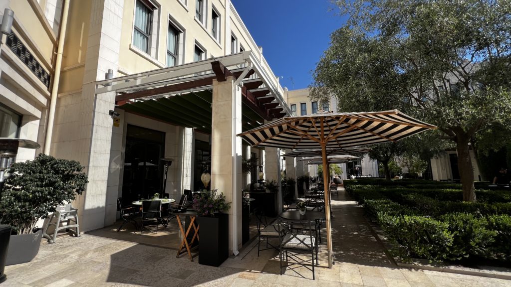 Une terrasse dans la cour d'un hôtel avec des parasols et de la végétation