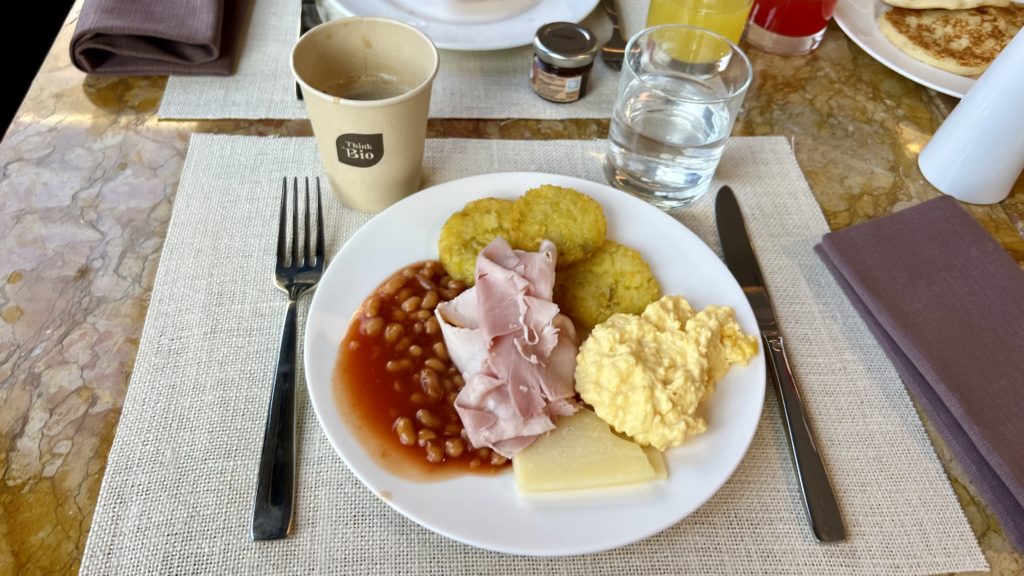 Une assiette de petit-déjeuner composée d’œufs, de viande, d'haricots accompagnée d'un café et d'eau aromatisée